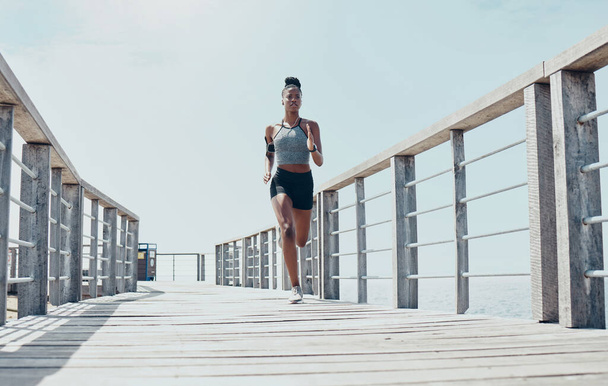 Fitness, esercizio fisico e corsa con donna nera sul ponte con allenamento mattutino per sport, salute e benessere. Motivazione, libertà ed energia con il runner training per maratona, obiettivi e visione. - Foto, immagini