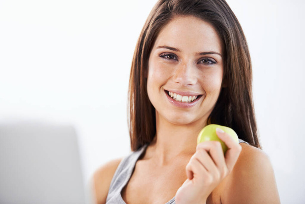Fuel to keep her browsing. Portrait of an attractive young woman eating a green apple - Fotó, kép