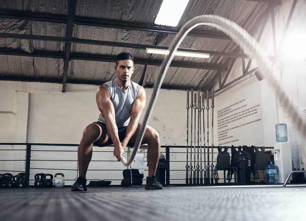 Rope, cardio and man training for fitness, body goal and health in the gym. Strong athlete with focus and energy doing exercise and workout for wellness, power and motivation at a sports club. - Photo, Image