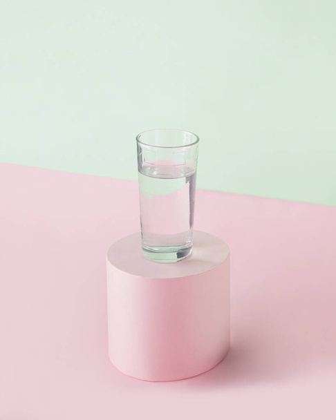 Egy pohár friss, tiszta víz egy elszigetelt pasztell rózsaszín és zöld háttérrel. Minimális absztrakt kreatív egészséges életmód jelenet. A tiszta víz ivása vagy a test hidratálása. - Fotó, kép
