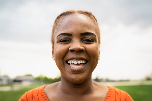 Onnellinen afrikkalainen nainen hymyilee kameran edessä puistossa - Valokuva, kuva