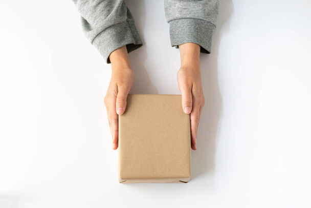woman hands taking a kraft box over white background, horizontal view - Photo, Image