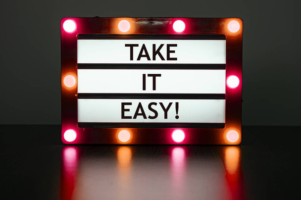 Lightbox with red lights in dark room with phrase- take it easy. - Фото, зображення