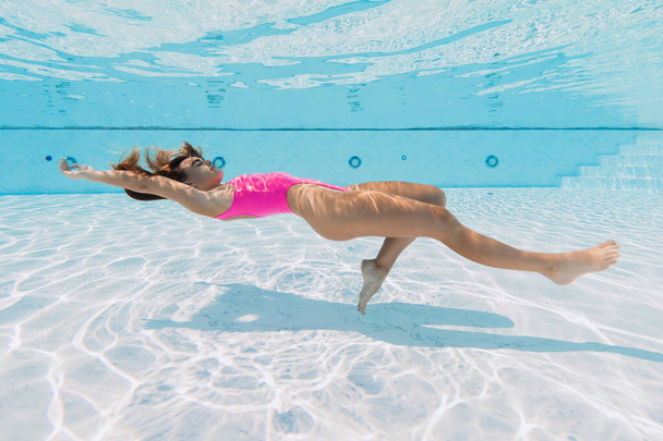 Atrakcyjna sportowa kobieta w różowych strojach kąpielowych relaks i pozowanie pod wodą w basenie - Zdjęcie, obraz