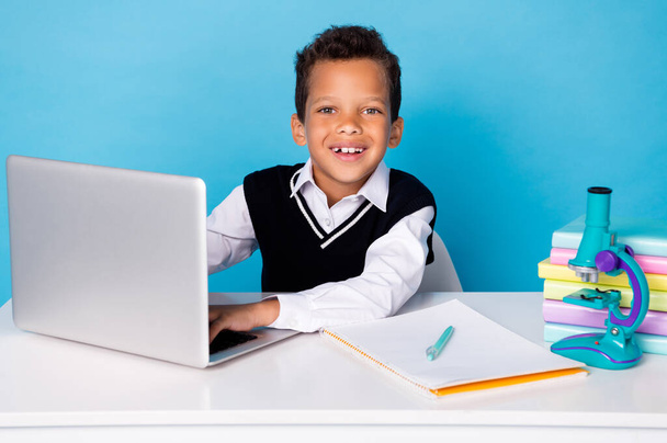 Portrait of smart cheerful boy use wireless netbook toothy smile isolated on blue color background. - Photo, Image