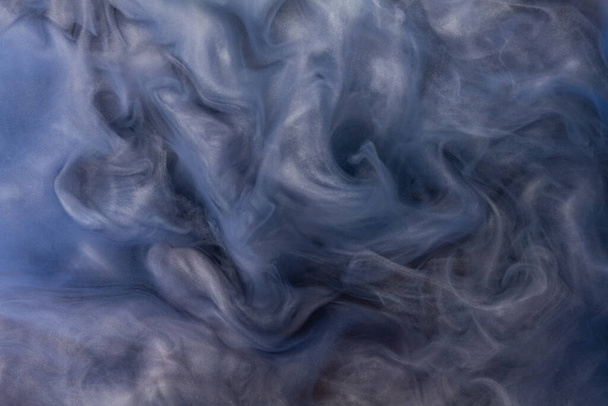 Echte shot kleur verf druppels in het water. Abstract blauwe Inkt wolk botsing geïsoleerd op blauwe achtergrond. Vloeibaar marmer patroon. Moderne kunst. Abstracte vloeistof acrylverf. - Foto, afbeelding