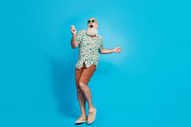 Full length size photo of senior excited positive good mood wear brown shorts shoes shirt dancing look funny outfit sale isolated on bright blue color background. - 写真・画像