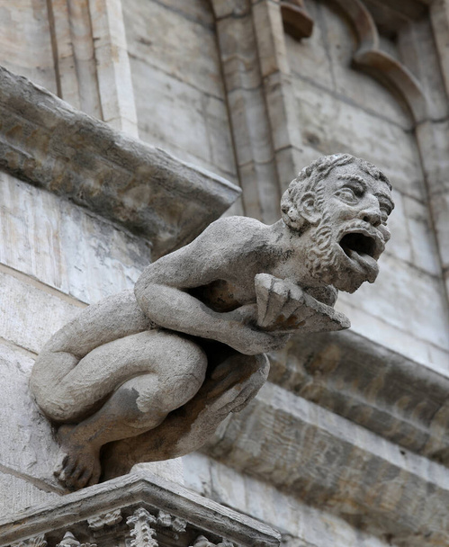 Monströse Statue mit fast menschlichen Zügen, Wasserspeier genannt, an der Fassade des historischen Gebäudes - Foto, Bild