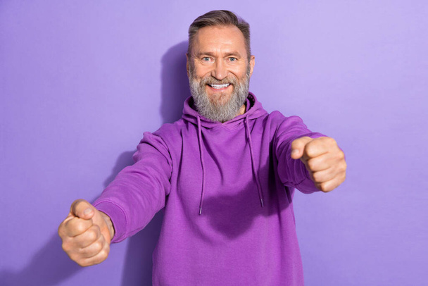 Portrait of handsome pensioner man dressed purple sweatshirt hands hold imaginary steering wheel isolated on violet color background. - Valokuva, kuva