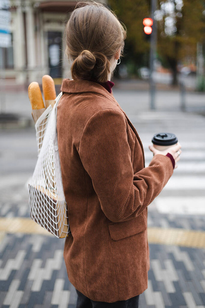 beautiful girl with baguettes and coffee walks around the cit - Foto, Imagen