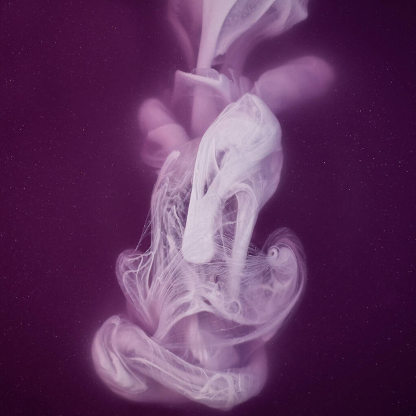 Echte Farbspritzer fallen ins Wasser. Abstrakte weiße Tintenwolkenkollision isoliert auf violettem Hintergrund. Flüssiges Marmormuster. Moderne Kunst. Abstrakte flüssige Acrylmalerei. - Foto, Bild