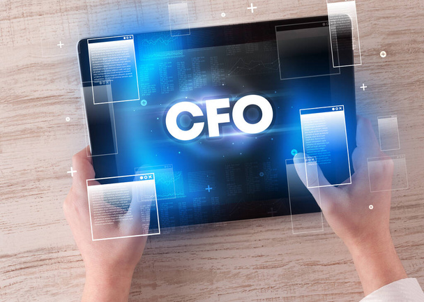Close-up of a hand holding tablet with CFO abbreviation, modern technology concept - Фото, изображение
