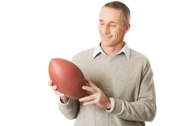 Portrait of mature man holding a rugby ball - 写真・画像