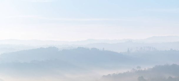 Capas de colinas en la niebla durante la mañana en otoño, paisaje brumoso rural - Foto, imagen