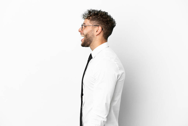 Zakelijke blanke man geïsoleerd op witte achtergrond lachen in laterale positie - Foto, afbeelding
