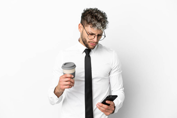 Επιχειρηματίας καυκάσιος άνθρωπος απομονωμένος σε λευκό φόντο κρατώντας καφέ για να πάρει μακριά και ένα κινητό - Φωτογραφία, εικόνα