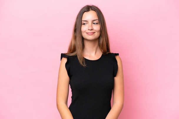 Young caucasian woman isolated on pink background having doubts while looking side - Фото, изображение