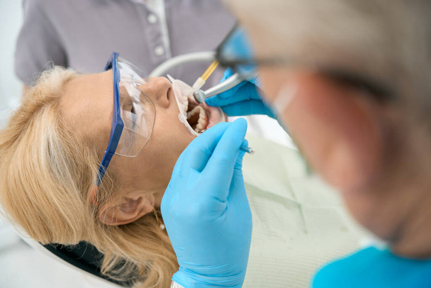 Close up side view portret pięknej białej kobiety otrzymuje leczenie zębów w centrum stomatologicznym - Zdjęcie, obraz