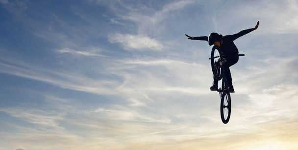 Mountainbike-Mann, Fallschirmsprung und Energie der Aktion, Freiheit und Wettbewerb Silhouette, Schatten und Attrappe. Radprofi in der Luft, Gefährdungslage und Fahrrad-Risiko auf Wolken. - Foto, Bild