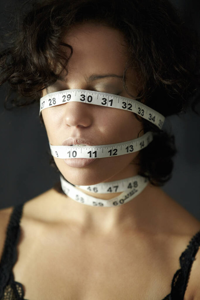Wrapped in self-loathing. A young woman wrapped in measuring tape - Photo, Image