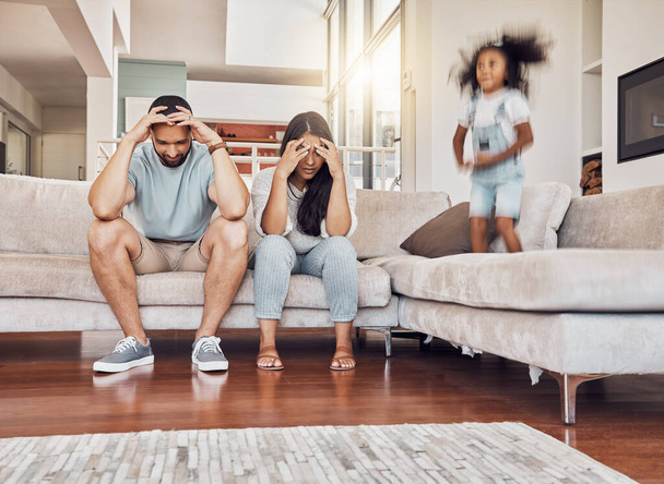 Tired parents, frustrated and active child being naughty and playful, adhd daughter playing by upset, stressed and depressed mother and father at home. Energy of girl kid jumping by man and woman. - Fotó, kép