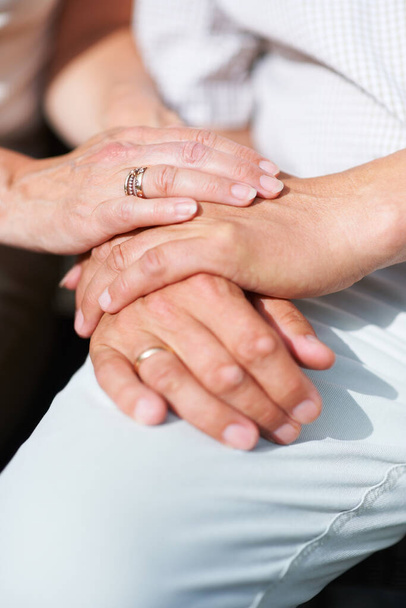 Sharing their lives. a senior couples hands resting on one another with their wedding rings showing - 写真・画像
