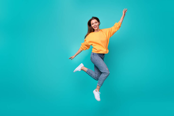 Full length photo of young adorable pretty cute woman wear orange sweater jean jump carefree celebrate party isolated on aquamarine color background. - Foto, immagini