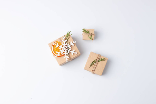 Рождественский минимальный состав с упаковкой подарков в ремесленной бумаге и розмарина на белом фоне. Отказ от концепции рождественских каникул. Квартира, копировальное пространство - Фото, изображение