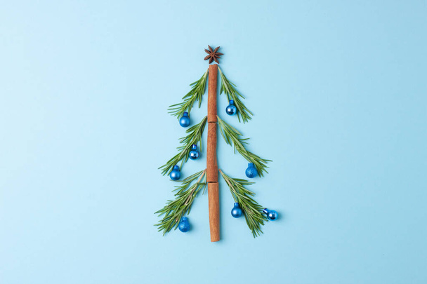 Christmas tree shape made with rosemary and balls blue background. Flat lay, copy space - Фото, зображення