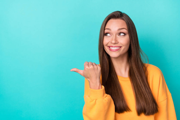Closeup photo of young gorgeous adorable girlish lady wear yellow sweater finger point empty space excited look information isolated on cyan color background. - Фото, зображення