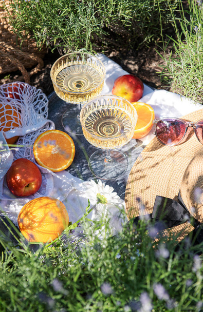 Καλοκαιρινό πικνίκ σε χωράφι με λεβάντα με ποτήρια σαμπάνιας και φρούτα - Φωτογραφία, εικόνα