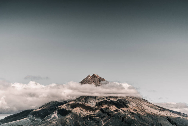rocky big mountain with lights and shadows created by the nice fluffy white clouds in a calm environment in the middle of nature, taranaki, new zealand - Travel concept - Foto, Imagen