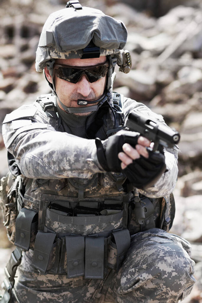Hes part of the infantry. a military man aiming a handgun - Foto, imagen