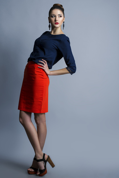 High fashion blik. Portret van een modieuze model met sexy rode lippen, mooie rode rok en blauw shirt. Studio opname - Foto, afbeelding