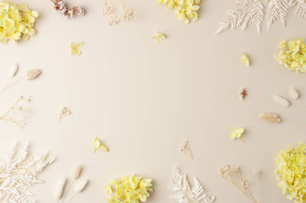 Cosmetic background with flowers on pastel beige. Flat lay, copy space - Zdjęcie, obraz