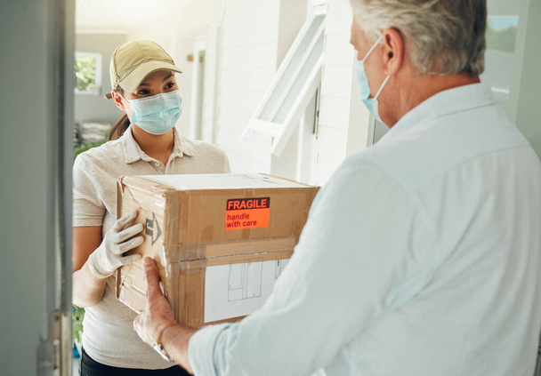 Online delivery worker, during covid pandemic does ecommerce box transport to door and with a mask on face. E commerce shopping industry, retail courier shipping service and safe package distribution. - Photo, image