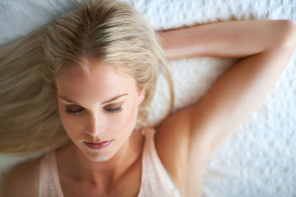 Catching some shut eye. An attractive young woman lying with her eyes closed on her bed - Fotoğraf, Görsel