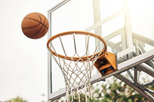 Basketball, net and ball flight in sports game outdoors for match in the USA. Sport and airball of throw to score point for win, victory against fiberglass board outside in a urban town or courtyard. - Фото, зображення