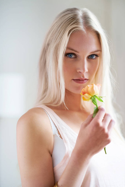 Milyen jó illat. Egy vonzó nő portréja, aki sárga rózsát szagol a hálószobájában. - Fotó, kép