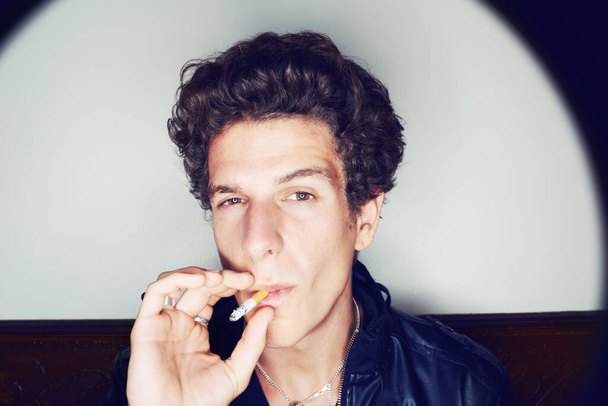 Taking a drag. Portrait of a young man inhaling deeply on a cigarette - Fotografie, Obrázek