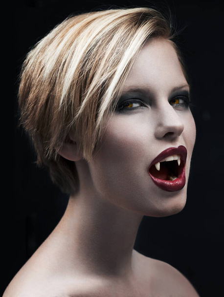Dont let her seduce you...A seductive female vampire baring her fangs and looking at you - Photo, Image