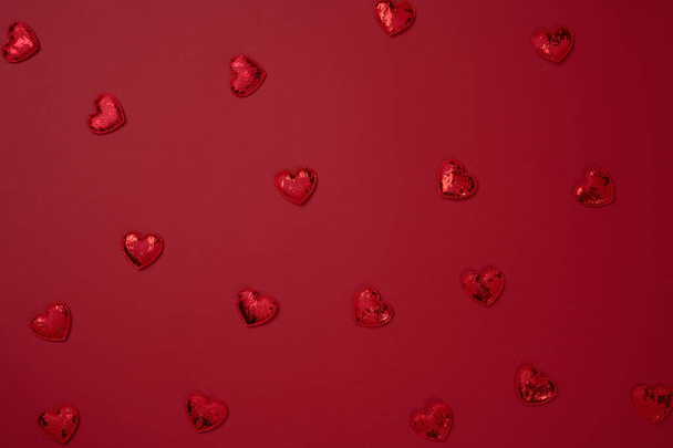Κόκκινη υφασμάτινη καρδιά σε κόκκινο φόντο χαρτιού, κορυφαία άποψη. - Φωτογραφία, εικόνα