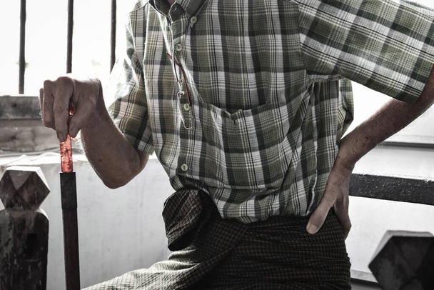 Aziatische oudere man die lijdt aan linkse onderrug en lendenpijn. Het kan worden veroorzaakt door mechanische of pathologische proces. - Foto, afbeelding