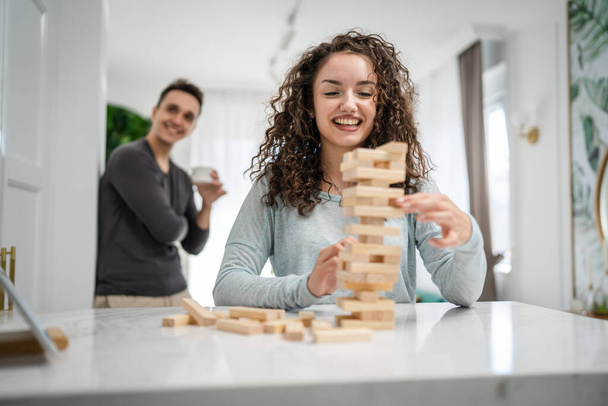 woman and man happy caucasian couple husband and wife or friends playing jenga table game at home having fun happy smile leisure time spending time together family time copy space real people - Photo, Image