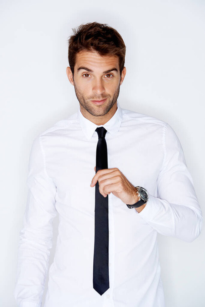 Looking sharp. Handsome young guy adjusting his tie against a white background - Photo, Image