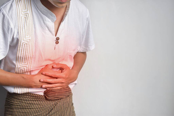 Jovem asiático sofrendo de dor abdominal superior. Pode ser causada por dor de estômago, enterite, colite, apendicite, hepatite, pancreatite, intoxicação alimentar, etc.. - Foto, Imagem