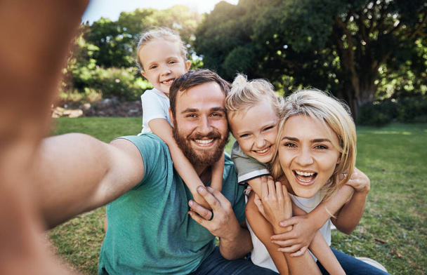 Naturaleza, selfie y retrato de una familia feliz en un picnic juntos en el jardín verde al aire libre. Feliz, sonrisa y los padres jugando, abrazando y vinculación con los niños fuera en el patio trasero o parque en Canadá - Foto, imagen