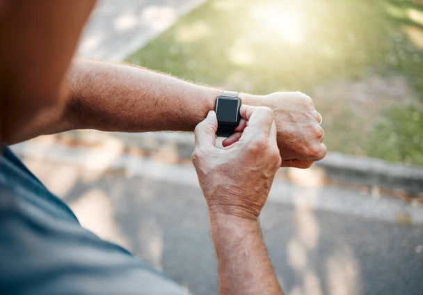 Man, street and running with smartwatch for heart reading, health and fitness on break. Runner, watch and road check time, speed or distance on workout, exercise or training outside for body wellness. - 写真・画像