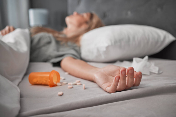 Depression, mental health and overdose with pills and woman in bedroom for anxiety, suicide and death. Sad, medicine and grief with girl lying in bed after taking drugs for pain, trauma and problem. - Foto, Imagem