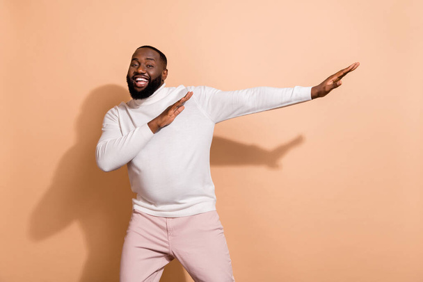 Photo of excited cheerful guy wear white sweater auto rider having fun isolated beige color background. - Photo, image